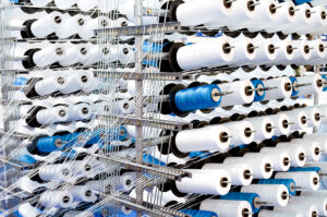 Bei der Herstellung von Textilien werden zahllose Garnrollen verbraucht. Bild: richterfoto/iStockphoto